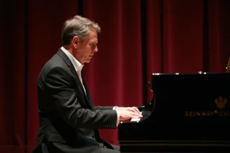 Pianiste français en costume noir jouant sur un Steinway à queue sur une scène de concert classique